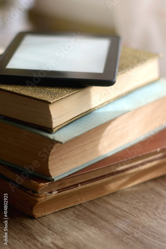 Stack of vintage books and e-book reader on top. Selective focus.