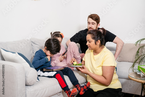 Young mixed-race family relaxing at home with digital devices. Real life, diversity, digintal technology