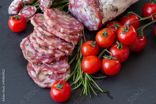 Sliced Air-dried salami with rosemary and cherry tomatoes - grey stone background