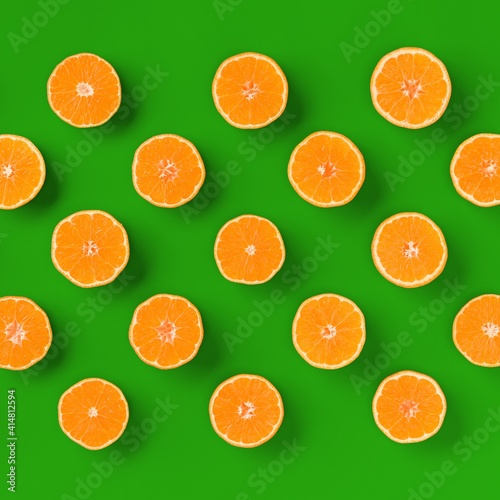 Fruit pattern of fresh orange tangerine or mandarin over green background. Flat lay, top view. Pop art design, creative summer concept. Citrus in minimal style..