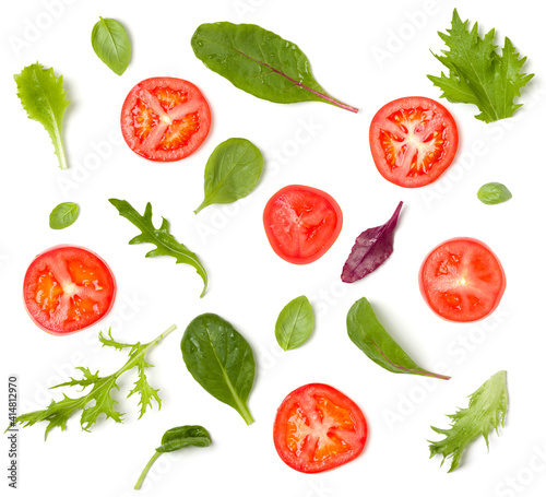 Creative layout made of tomato slices and lettuce salad leaves. Flat lay, top view. Food concept. Vegetables isolated on white background. Food ingredients pattern.