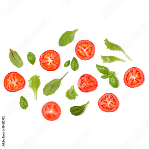 Creative layout made of tomato slices and lettuce salad leaves. Flat lay, top view. Food concept. Vegetables isolated on white background. Food ingredients pattern.