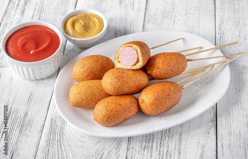 Naklejka Corn dogs on white serving plate