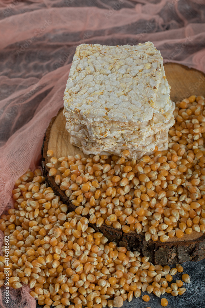 Delicious crispbread and raw corn seeds on wood piece Delicious crispbread and raw corn seeds on wood piece