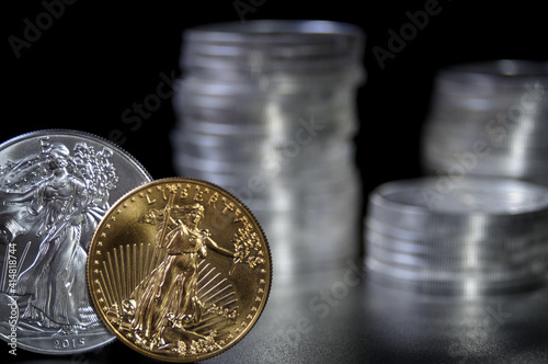 Gold and silver one ounce coins infront of stacks of silver coins