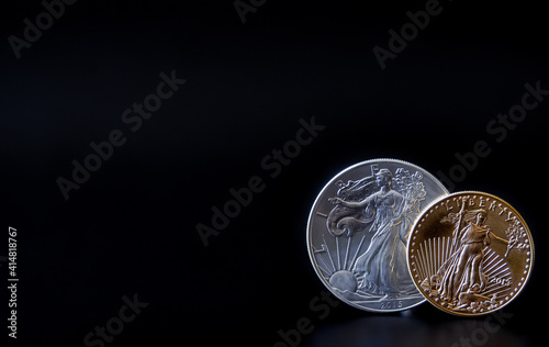 A gold and silver coin in corner of a black backdrop