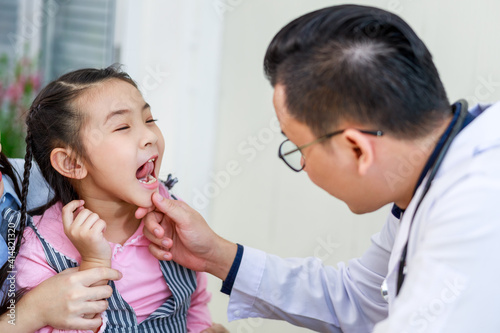 Dentist examining teeth of little girl at dental clinic