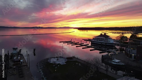 Gorgeous pink sunset reflection on lake with silhouetted boats and docks in foreground. Aerial 4K drone video filmed on Lake Champlain in Burlington, Vermont. photo