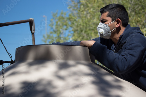 Hombre revisando suministro de agua después de corte. Usa mascarilla KN95 por la pandemia photo