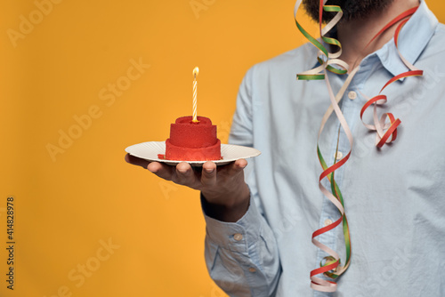 A man holding a cake in a plate and a candle from above isolated background
