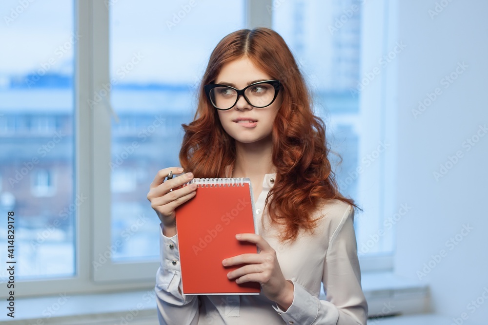 red-haired business woman wearing glasses red notepad Professional red-haired business woman wearing glasses red notepad Professional