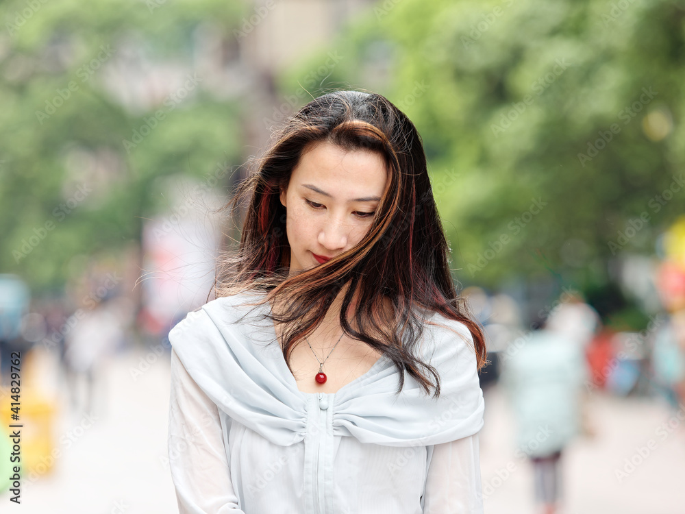 Beautiful woman walking on Nanjing road in Shanghai with her head down in windy day.