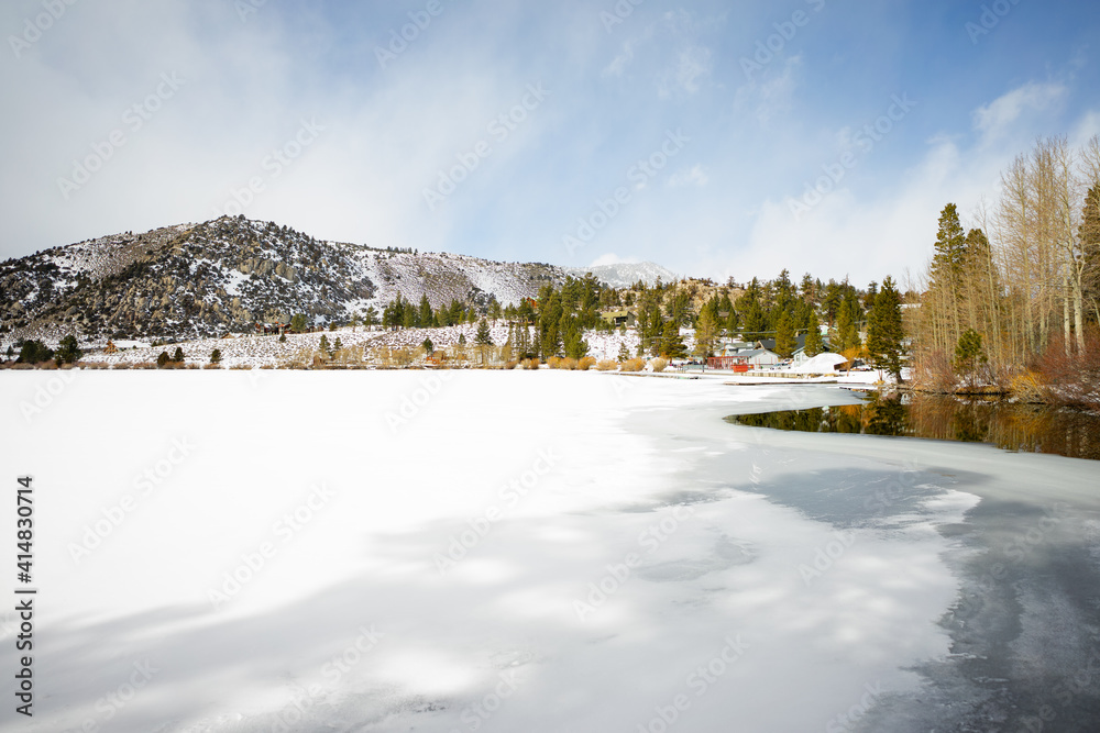Snow over a frozen lake and snow covered mountains in winter