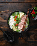 Pho Bo vietnamese soup with beef and noodles on a wooden background, view from above
