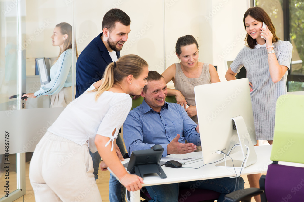 Obraz premium Positive business team working together in modern office, looking at computer screen