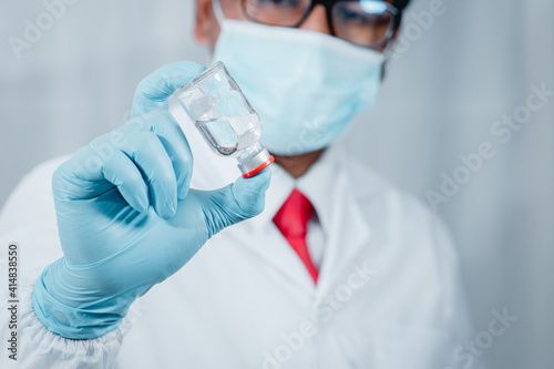 Doctor or scientist wearing antivirus clothing In the laboratory, research laboratories are studying and developing a medical vaccine, COVID-19, holding a syringe with a liquid vaccine.