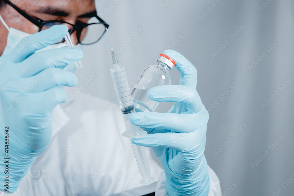 Doctor or scientist wearing antivirus clothing In the laboratory, research laboratories are studying and developing a medical vaccine, COVID-19, holding a syringe with a liquid vaccine. Doctor or scientist wearing antivirus clothing In the laboratory, research laboratories are studying and developing a medical vaccine, COVID-19, holding a syringe with a liquid vaccine.