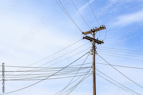 Utility Pole with Many Lines against a Cloudy Blue Sky