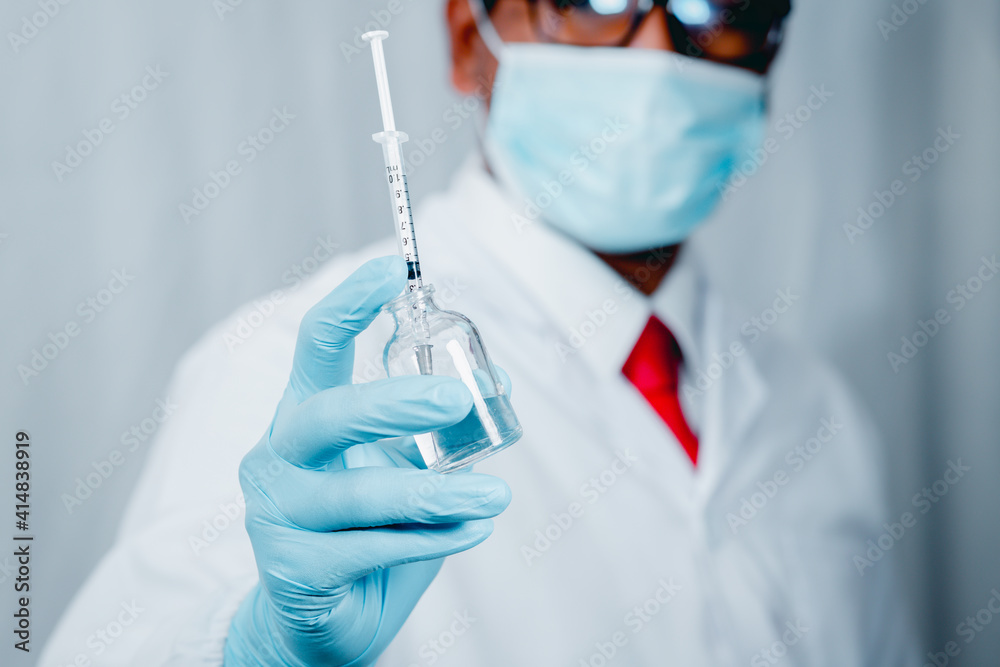 Doctor or scientist wearing antivirus clothing In the laboratory, research laboratories are studying and developing a medical vaccine, COVID-19, holding a syringe with a liquid vaccine. Doctor or scientist wearing antivirus clothing In the laboratory, research laboratories are studying and developing a medical vaccine, COVID-19, holding a syringe with a liquid vaccine.