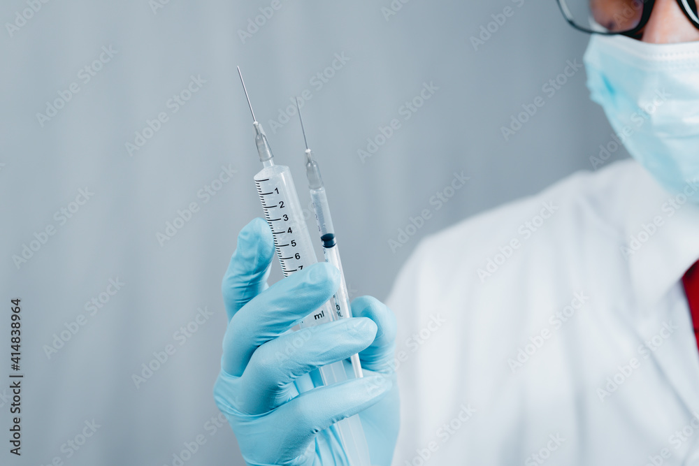 Doctor or scientist wearing antivirus clothing In the laboratory, research laboratories are studying and developing a medical vaccine, COVID-19, holding a syringe with a liquid vaccine. Doctor or scientist wearing antivirus clothing In the laboratory, research laboratories are studying and developing a medical vaccine, COVID-19, holding a syringe with a liquid vaccine.