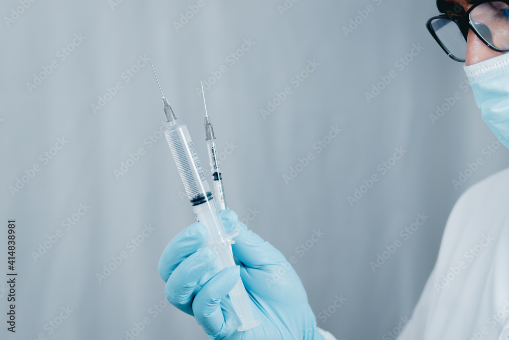 Doctor or scientist wearing antivirus clothing In the laboratory, research laboratories are studying and developing a medical vaccine, COVID-19, holding a syringe with a liquid vaccine. Doctor or scientist wearing antivirus clothing In the laboratory, research laboratories are studying and developing a medical vaccine, COVID-19, holding a syringe with a liquid vaccine.