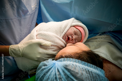 Mommy and baby newborn in the Cesarean section. First day of Little Baby Newborn Life  in this world. First sight of mom and her newborn in operation room