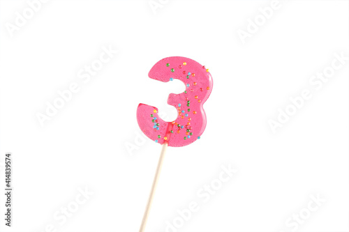 lolipop in number 3 shape. sweet candy on wooden stick. pink number 5 isolated on a white background. anniversary selebration or birthday party.