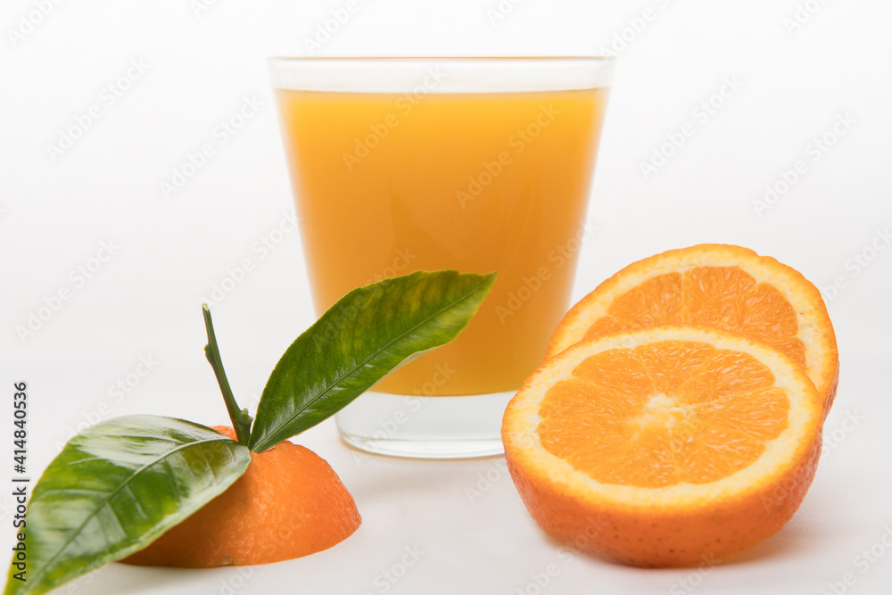 orange juice in glass with pieces of oranges and green leafs on black background. Summer and freshness concept orange juice in glass with pieces of oranges and green leafs on black background. Summer and freshness concept