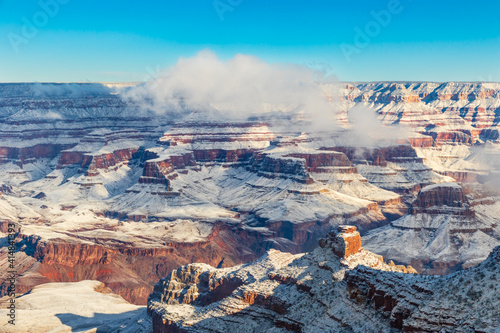 Grand Canyon in the morning, covered in snow. Blue sky; clouds on rim of canyon.
 photo