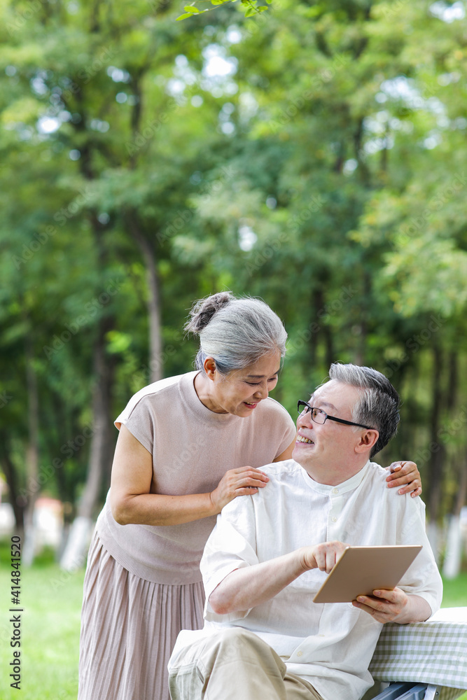Happy elderly couples use tablet computers to surf the Internet outdoors