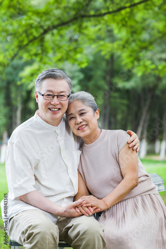 Happy old couple sitting on chairs in outdoor park