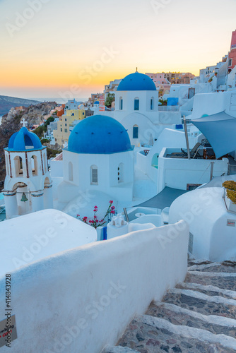 Sunset view of churches and blue cupolas of Oia town at Santorini, Greece photo