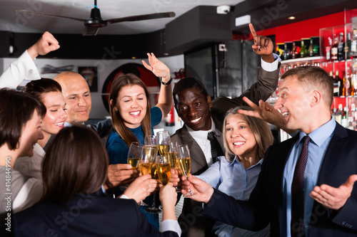 International group of smiling businesspeople toasting with champagne, having fun at office party in nightclub