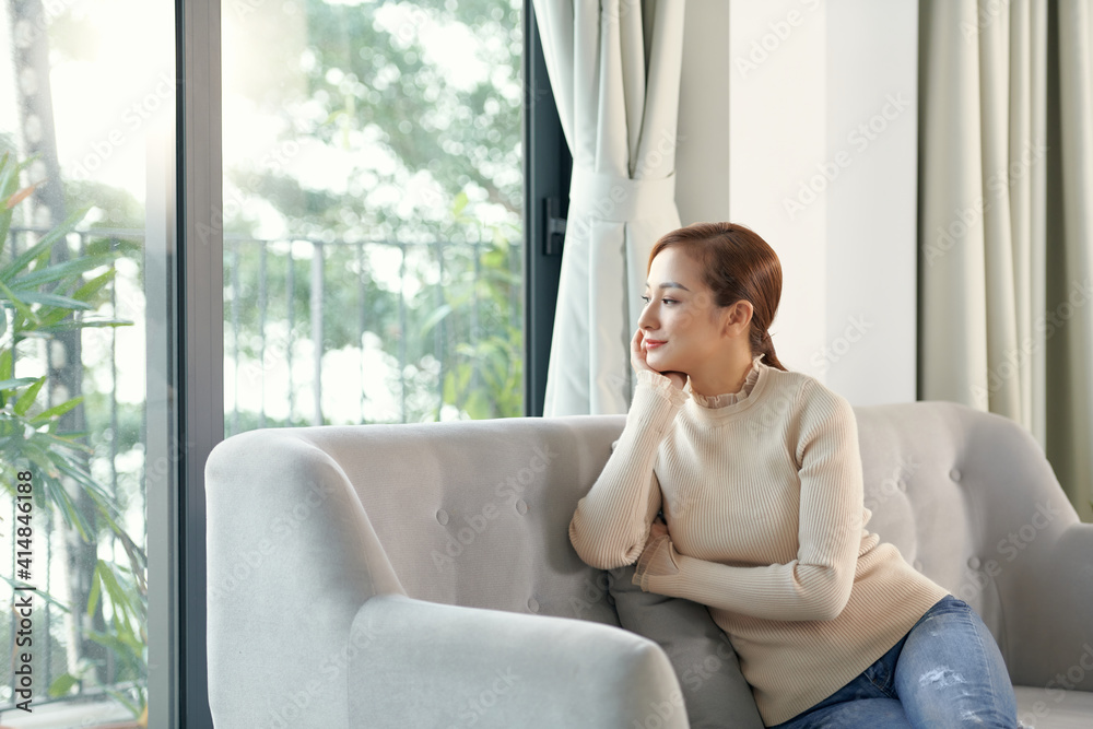 Attractive peaceful young woman with cup of tea sitting and dreaming on sofa at home Attractive peaceful young woman with cup of tea sitting and dreaming on sofa at home