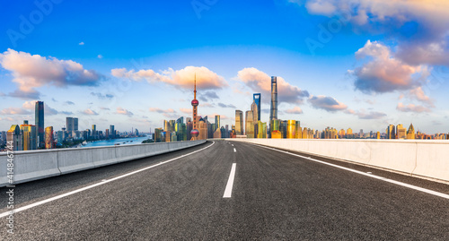 Empty asphalt road and Shanghai skyline with buildings at sunset.