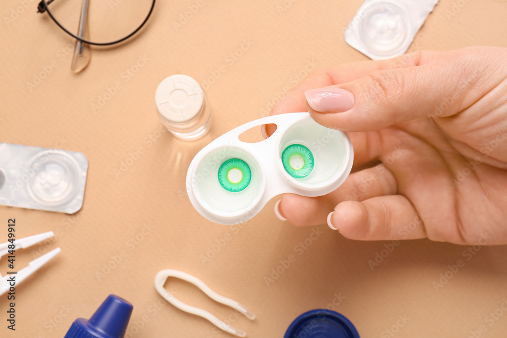 Female hand and container with contact lenses on color background Female hand and container with contact lenses on color background