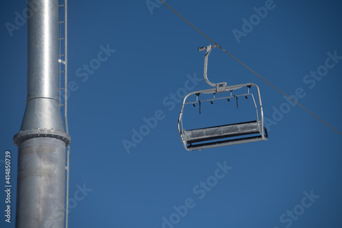 empty ski lift chair against blue skies silver metallic chair on cable line at ski resort horizontal format space for type  photo