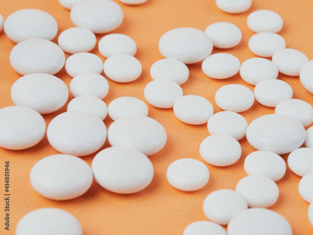 various white tablets on an orange background