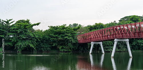 A metal bridge across a mountain river. Red iron bridge on a river near a forest