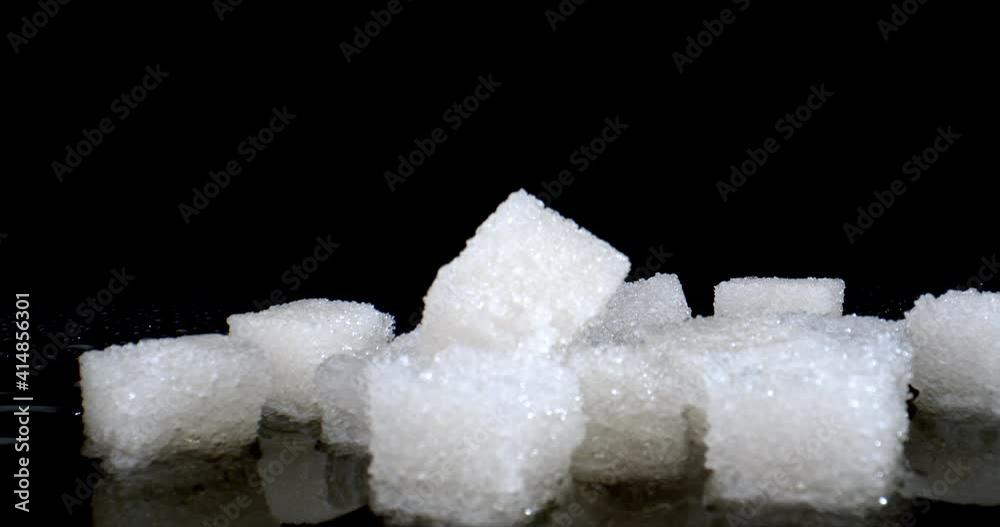 Close up of white pieces of sugar, concept of diabetes and obesity. Sugar cubes.on wet black table. High quality. Close up of white pieces of sugar, concept of diabetes and obesity. Sugar cubes.on wet black table. High quality.