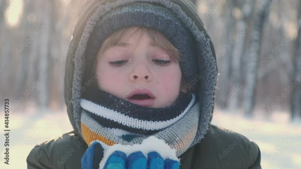 Portrait of smiling child playing with snow outdoors. Close up of boy having fun in winter park with friends in vacation and holidays. Emotion, happiness, lifestyle concept. Portrait of smiling child playing with snow outdoors. Close up of boy having fun in winter park with friends in vacation and holidays. Emotion, happiness, lifestyle concept.