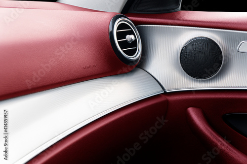 Car door handle inside the luxury modern car with red leather texture with stitching. Switch button control. Modern car interior details. Red perforated leather