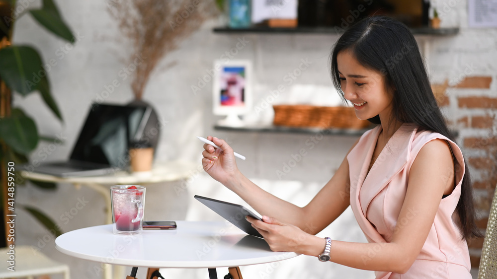Young stylish woman sitting in cafe and using digital tablet.
