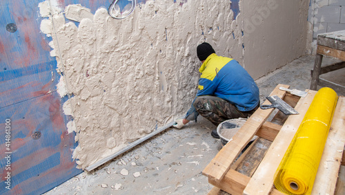 A worker plasters the walls in the room.
