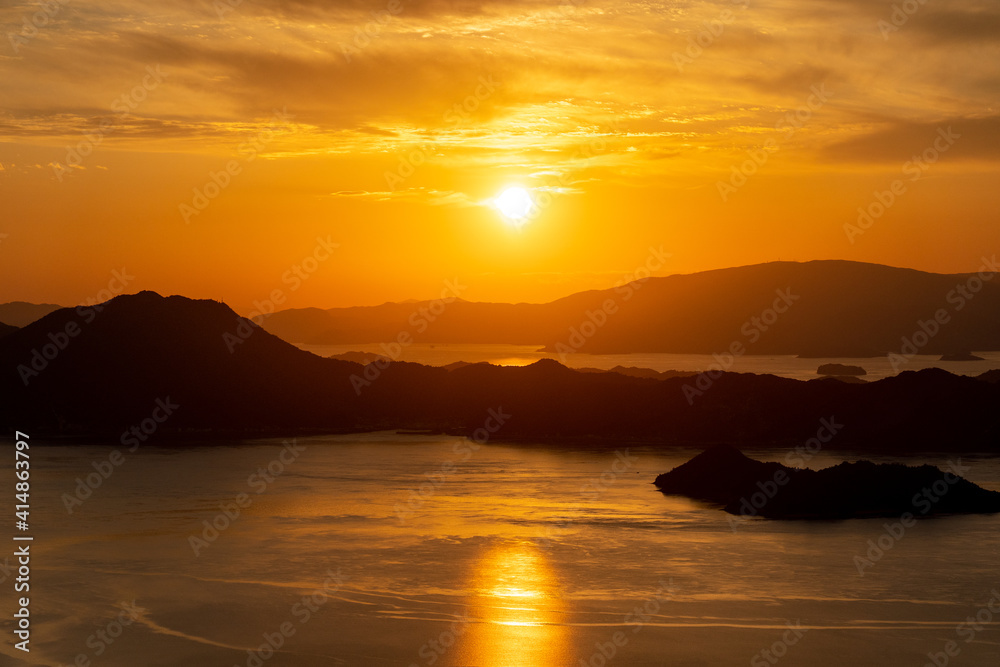 オレンジ色の夕焼けと海面に映る夕日