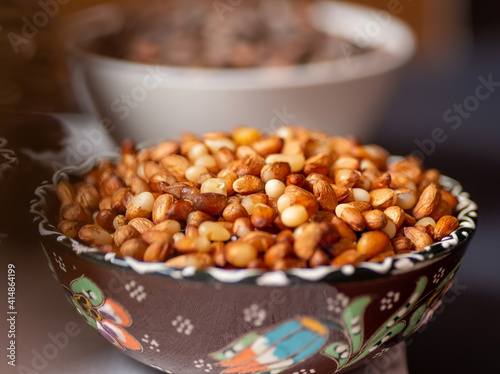 Brown ceramic bowl with peeled Siberian pine nuts. 