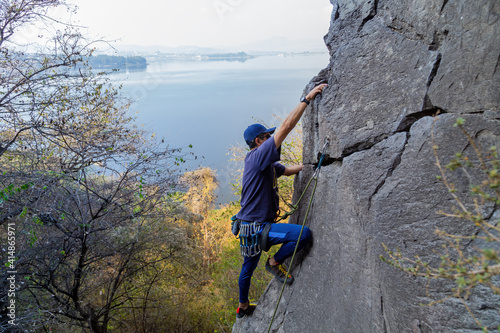Young Hispanic man with a rope engaged in the sports of rock climbing on the rock