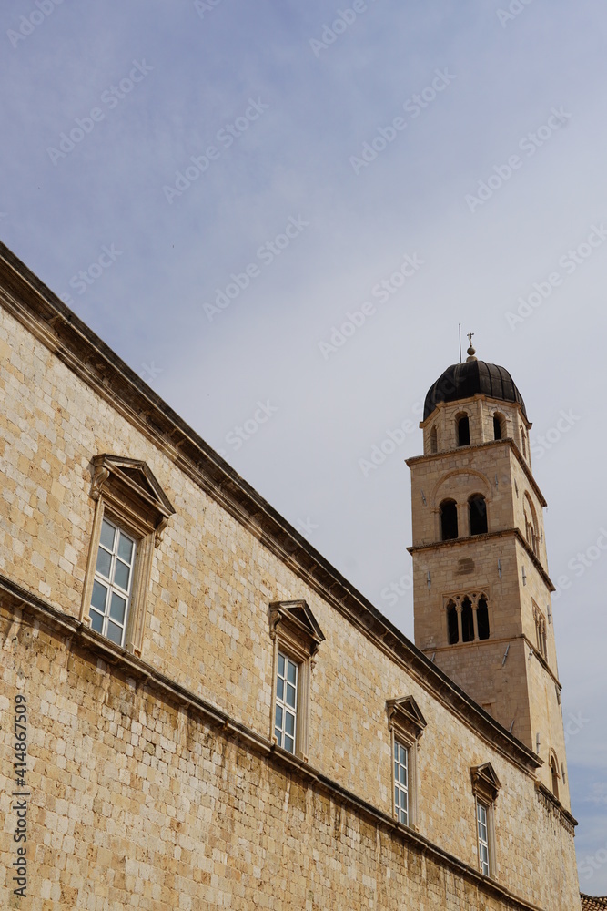 The old bell tower in Dubrovnik, a tall large bell tower, and part of a large church