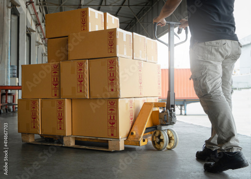 Woker working with hand pallet truck. worker unloading cardboard boxes stack on pallet rack. Shipment boxes. Cargo warehousing.