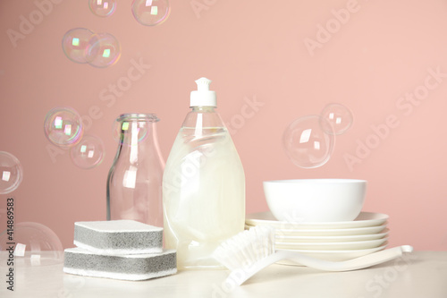 Cleaning tools, plates and soap bubbles on pink background. Dish washing supplies © New Africa